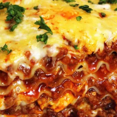 Lasagna dish serve with steam vegetables and garlic rolls